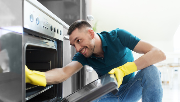 man with rag cleaning inside oven at home kitchen